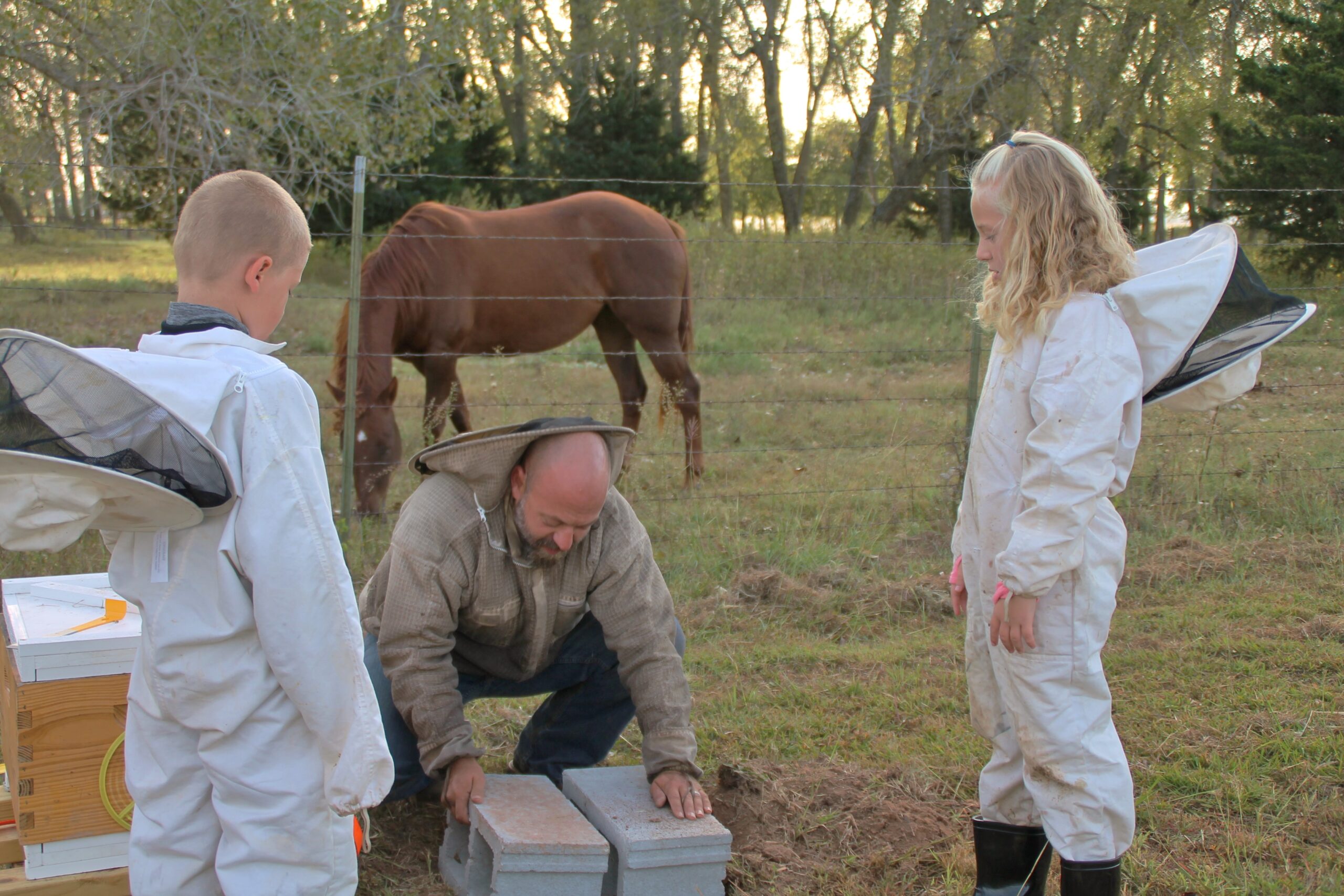 From left: Lucas, Justin and Lexi Scott set up beehives on a rural Canadian County property. Photo by Carol Mowdy Bond.