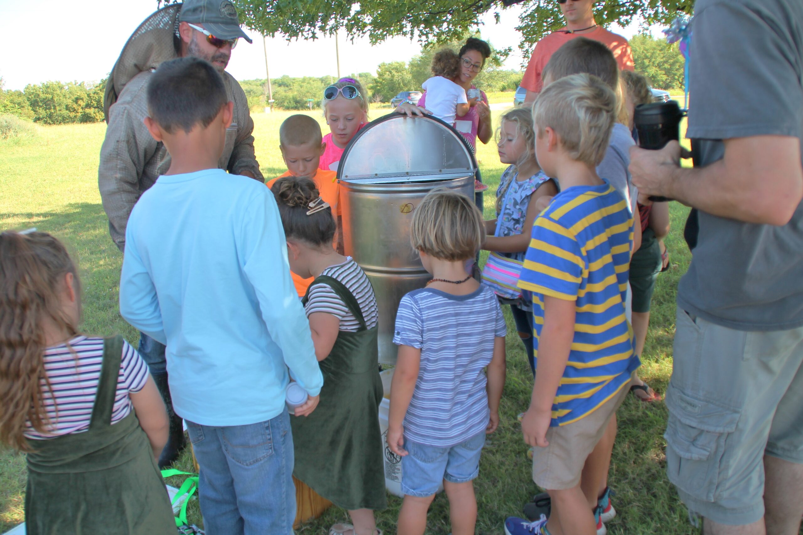 Top left: Justin Scott shows school children how to extract honey. Photo by Carol Mowdy Bond.