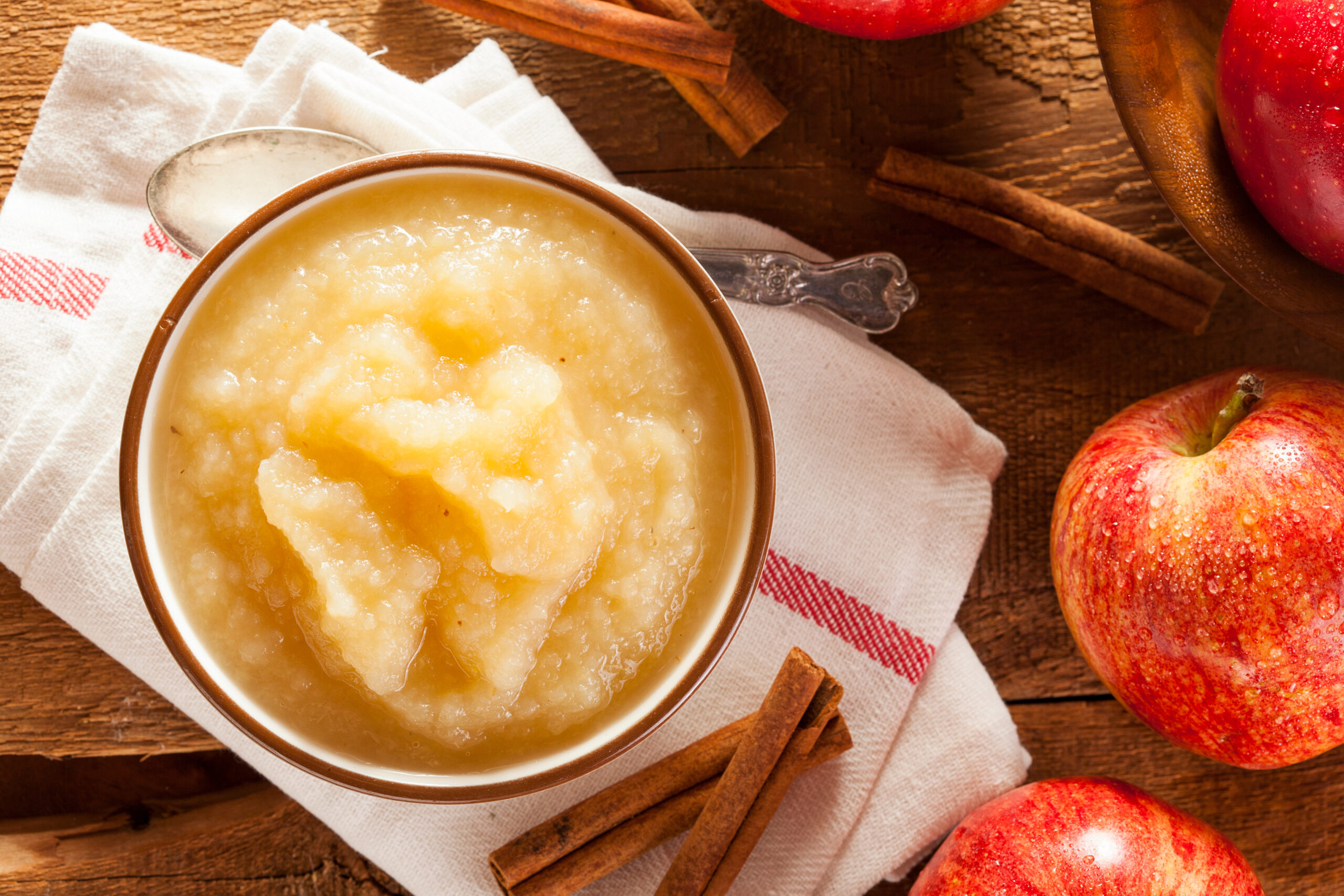 Bowl of applesauce with fresh apples and cinnamon sticks